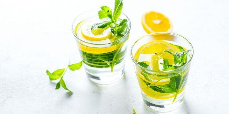 Infused water in glasses on white background. Healthy food drink concept. Closeup with copy space.